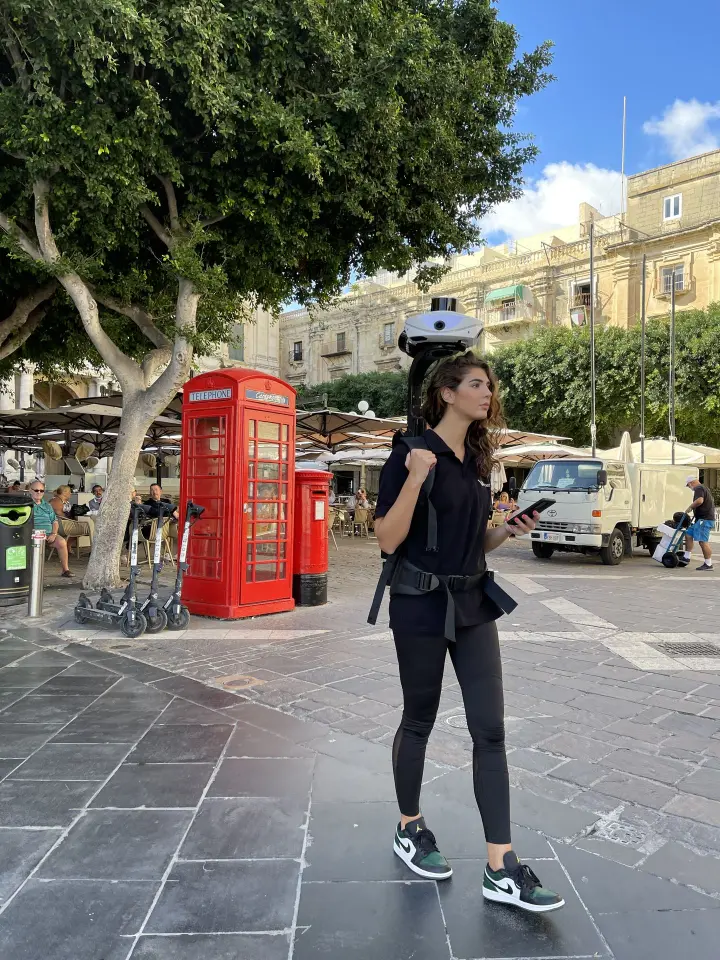 Een vrouw scant een voetgangerszone in het stadscentrum met de Viametris MS-96 mobiele LiDAR scanner als rugzak, terwijl ze de data live controleert op haar smartphone.