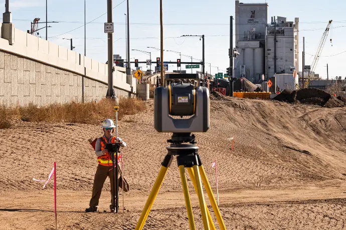 De Trimble SX12 scanning total station op een actieve bouwwerf voor nauwkeurige maatvoering en het vastleggen van de voortgang in een puntenwolk.